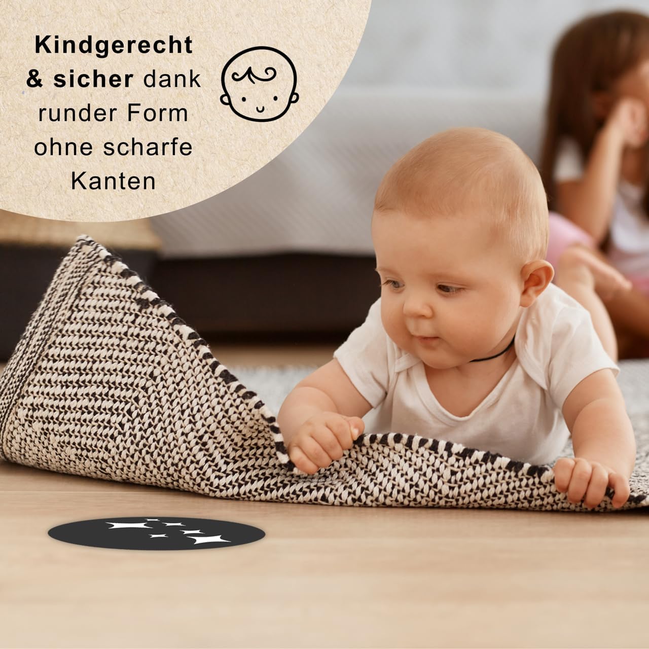 Ein Baby schaut eine Kontrastkarte an und trainiert dabei das Liegen auf dem Bauch. 