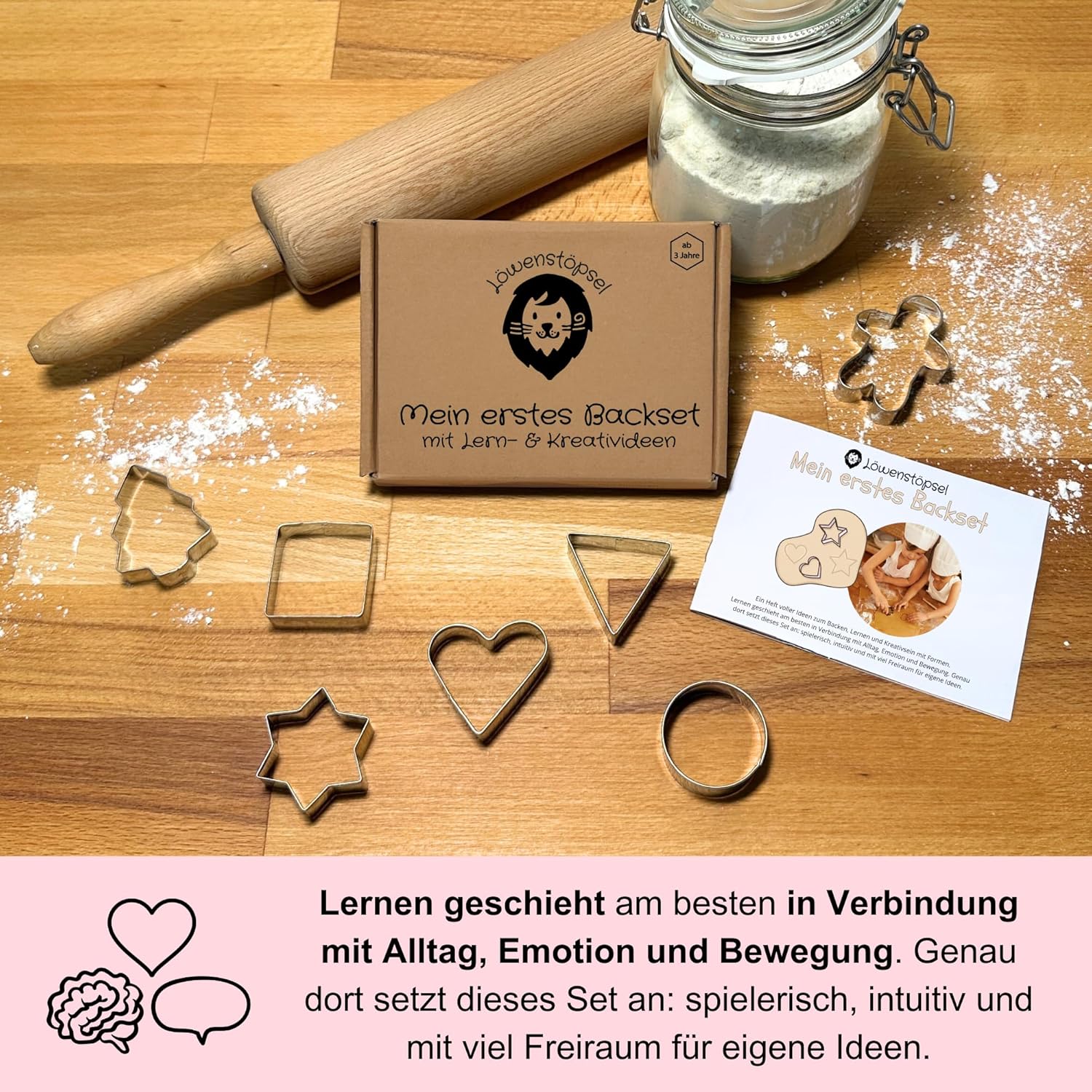 Mein erstes Backset mit 7 Ausstechformen, Begleitheft und Lernideen, arrangiert auf Backtisch.